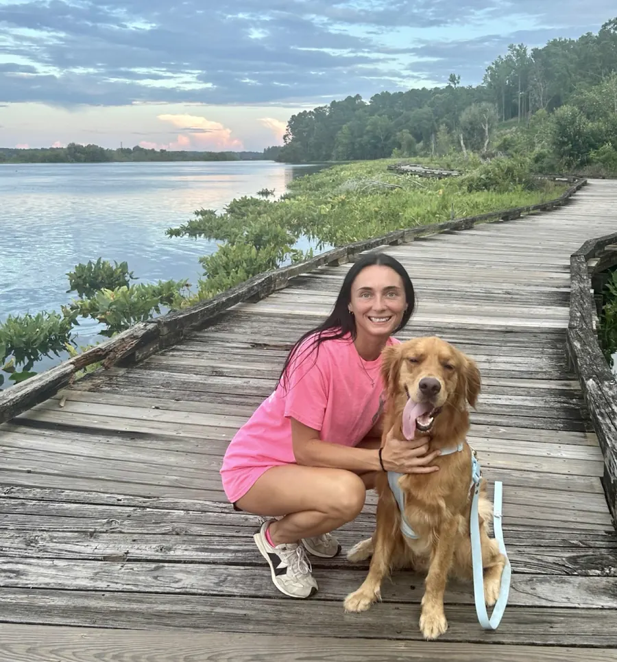 Allison with Duke, a golden retriever, on a boardwalk